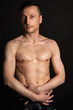 © vladorlov - Adult attractive man with a beautiful body posing in the studio. Black background.