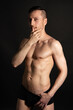 © vladorlov - Adult attractive man with a beautiful body posing in the studio. Black background.