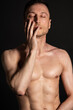 © vladorlov - Adult attractive man with a beautiful body posing in the studio. Black background.