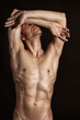 © vladorlov - Adult attractive man with a beautiful body posing in the studio. Black background.