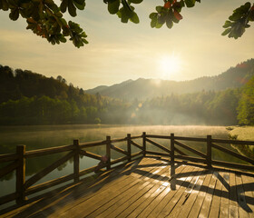 Sticker - Wooden pier on the calm lake at sunset. Beautiful lake and tree branches in sunset light