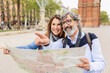 © Xavier Lorenzo - Happy senior adult tourist couple holding city map while visiting Barcelona on vacation. Married middle aged man and woman looking for touristic location enjoying summer holidays together. Retirement