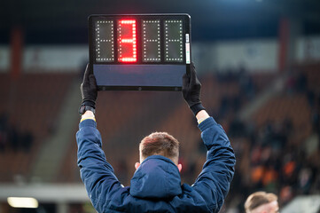 Wall Mural - Sideline referee shows 4 minutes added time during the football match.