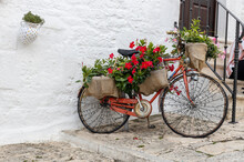 Beautiful view of a decorative old bicycle with flowers and a garland in Ostuni.