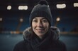 Portrait of smiling woman in cap and scarf in ice hockey rink