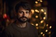 © Robert MEYNER - Portrait of a handsome man with a beard in a sweater on a background of a Christmas tree.