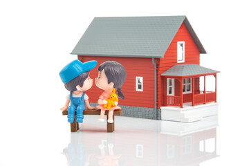 miniature people. romantic couple of young people near the house model on a white background. friendship and great relationship