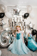 © Serhii - The girl is dressed in a blue dress of Elsa. Happy child celebrating a birthday party 6 years. Photo wall, photo zone decoration white, black, silver balloons. Idea decor an arch in luxury style.