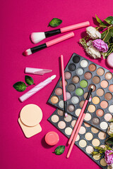 Make up set with colorful eyeshadow palettes, brushes, sponges and flowers. Viva magenta background