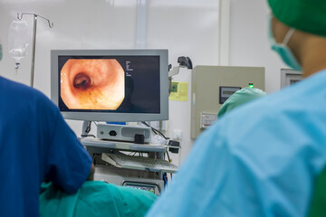 A doctor or surgeon in a light blue protective gown did a colonoscopy or gastroscopy inside operating theatre in the hospital.EGD technology for cancer screening.Blur green background and foreground.