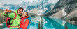 © Maridav - Couple travel selfie banner landscape happy hikers in winter alps lake view. Asian woman, Caucasian man using mobile phone