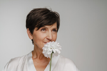 Senior woman smelling flower isolated over white background