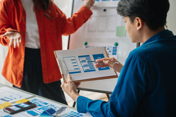  UX developer and ui designer brainstorming about mobile app interface wireframe design with customer breif and color code at modern office.
