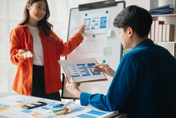  UX developer and ui designer brainstorming about mobile app interface wireframe design with customer breif and color code at office...