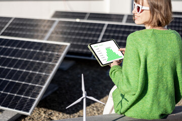 Young woman monitors energy production from the solar power plant with a digital tablet. View on tablet screen with running program. Concept of new technologies in alternative energy