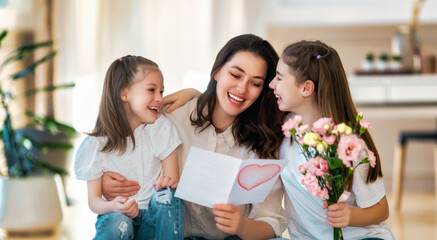 Daughters giving mother bouquet of flowers.