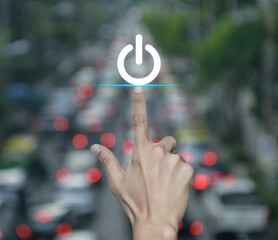 Wall Mural - Hand pressing power button icon over blur of rush hour with cars and road in city, Start up business concept