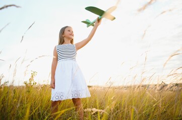 Wall Mural - Happy kid with toy plane is playing at sunset