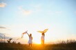 © Serhii - Happy children launch a kite in the field at sunset. Little boy and girl on summer vacation.