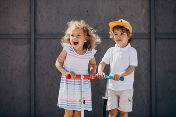 Boy and a girl riding scooter together in park