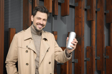 Wall Mural - Happy man holding tin can with beverage outdoors. Space for text