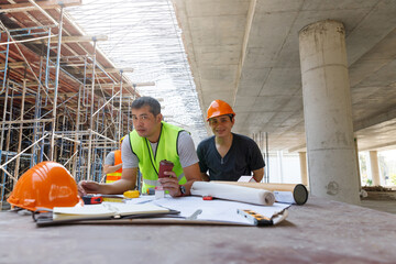 Construction concept of Engineer and Architect working with construction model and blueprint at construction site, Engineer and Architect discussing construction plan at building site