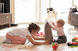 © Vera - Two happy sisters play on floor in home with pillow. kids have fun and laughing. children enjoy together. love and care in family.