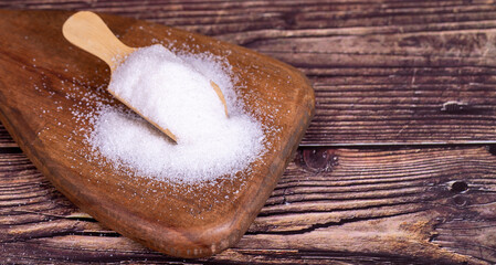 Wall Mural - White refined sugar on wood background. Powdered sugar in a wooden spoon. Copy space. Empty space for text