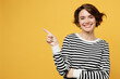 Young woman in casual striped black and white shirt point index finger aside indicate on workspace area copy space mock up isolated on plain yellow color background studio portrait Lifestyle concept
