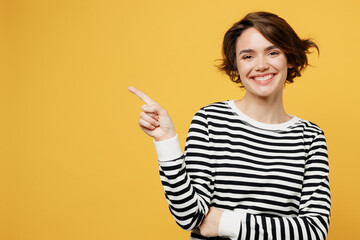 Wall Mural - Young woman in casual striped black and white shirt point index finger aside indicate on workspace area copy space mock up isolated on plain yellow color background studio portrait Lifestyle concept