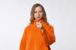 © Red Cristal - It's your fault. Portrait of disappointed young woman frowning, pointing index finger at camera, being mad, blaming all her failures on you, stands in orange sweater against neutral studio background