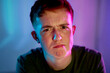 © Westend61 - Young man with facial expression with illuminated neon light on face