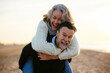 © Westend61 - Happy mature man giving piggyback ride to woman at beach