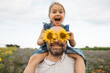 © Westend61 - Sunflowers covering eyes of playful man with daughter in a field
