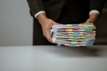 Businesswoman working in stacks of paperwork files for searching infomation unfinished documents about pile audit form on desk office and investigate financial doc in busy workload