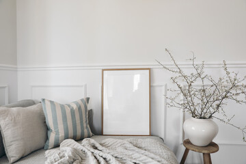 Wall Mural - Spring home decor. Elegant scandinavian living room interior. Wooden picture frame, poster mockup on sofa. Linen striped cushions, throw. Blurred background. Cherry plum blossoms in vase, wooden stool
