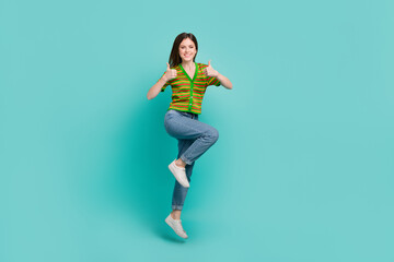 Poster - Full length photo of excited confident woman dressed striped cardigan showing two thumbs up jumping high isolated teal color background