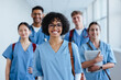 © Jacob Lund - Portrait of a young nursing student standing with her team in hospital, dressed in scrubs