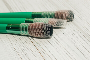 Wall Mural - Green makeup brushes on a wooden table.