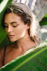Wall Mural - beautiful and natural looking woman with tropical banana leaves