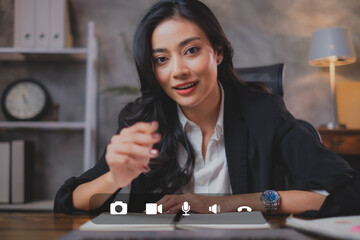 A business woman is using Video call on laptop to make an online conference. A beautiful confidence female employee is pointing at screen while presenting, consulting or meeting. Social media use.