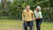 © amnaj - A wife helping her elderly husband patient use a walker to learn to walk. Elderly couple. Asian elderly couple giving love to each other smiling happily. Love and care for each other.