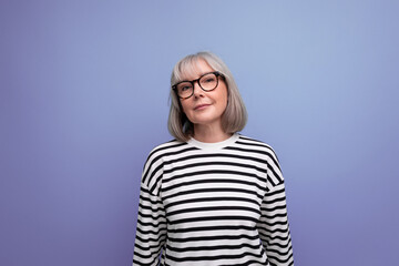 close-up portrait of an old woman with gray hair smiling kindly against a bright studio background