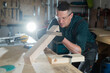 © Михаил Решетников - Carpenter measures a wooden board while working in a workshop.