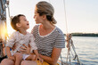 Attractive mother with her adorable toddler son sailing in sea on sailboat
