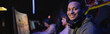 © LIGHTFIELD STUDIOS - Positive indian gamer with headphones looking at camera in cyber club, banner.