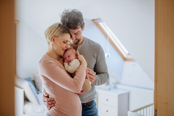 Parents cuddling their newborn baby in their home.