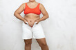 © Юля Бурмистрова - Hands of overweight woman pull white denim shorts over large belly, white background. Woman in red underwear try to squeeze into jeans. Overeating, fat body, plus size people, body positive.
