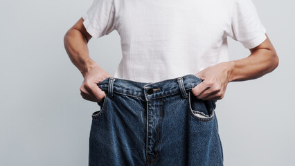 Young confident asian chinese weight loss man with oversize of jean pants.