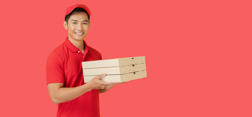 Wall Mural - The smiling pizza delivery man stands on a red background holding the pizza box and wearing a red cap and a blank t-shirt uniform.